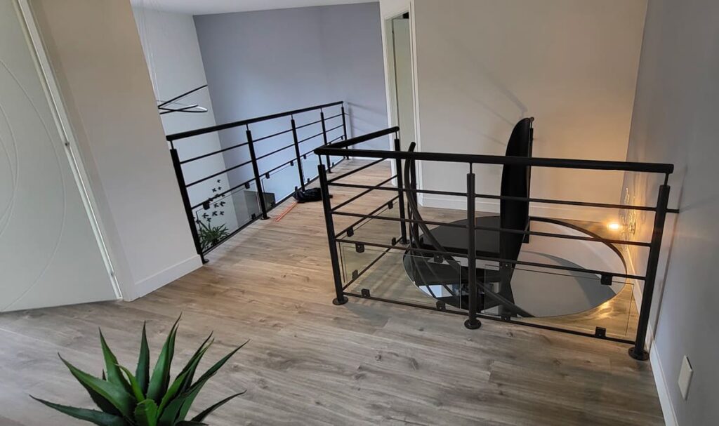 mezzanine avec les garde-corps noirs et l'escalier en colimaçon.